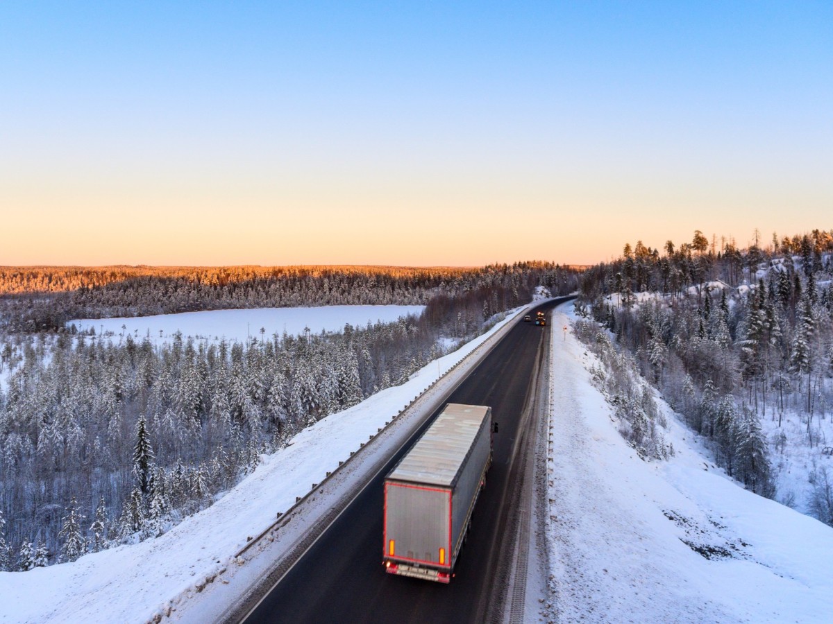 semi truck driving with snow alongside of road