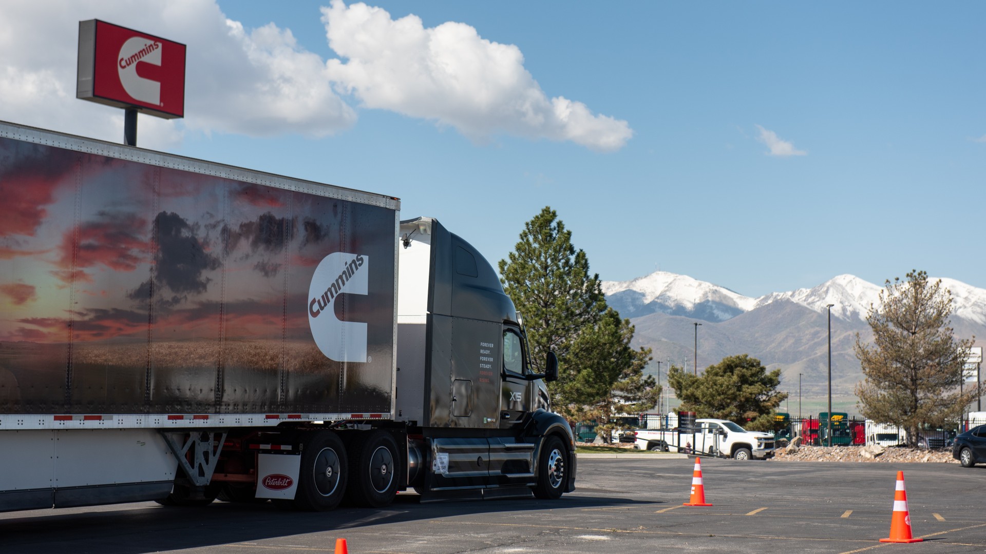 Cummins Forever Rising Tour branded truck parked with a Cummins sign behind it