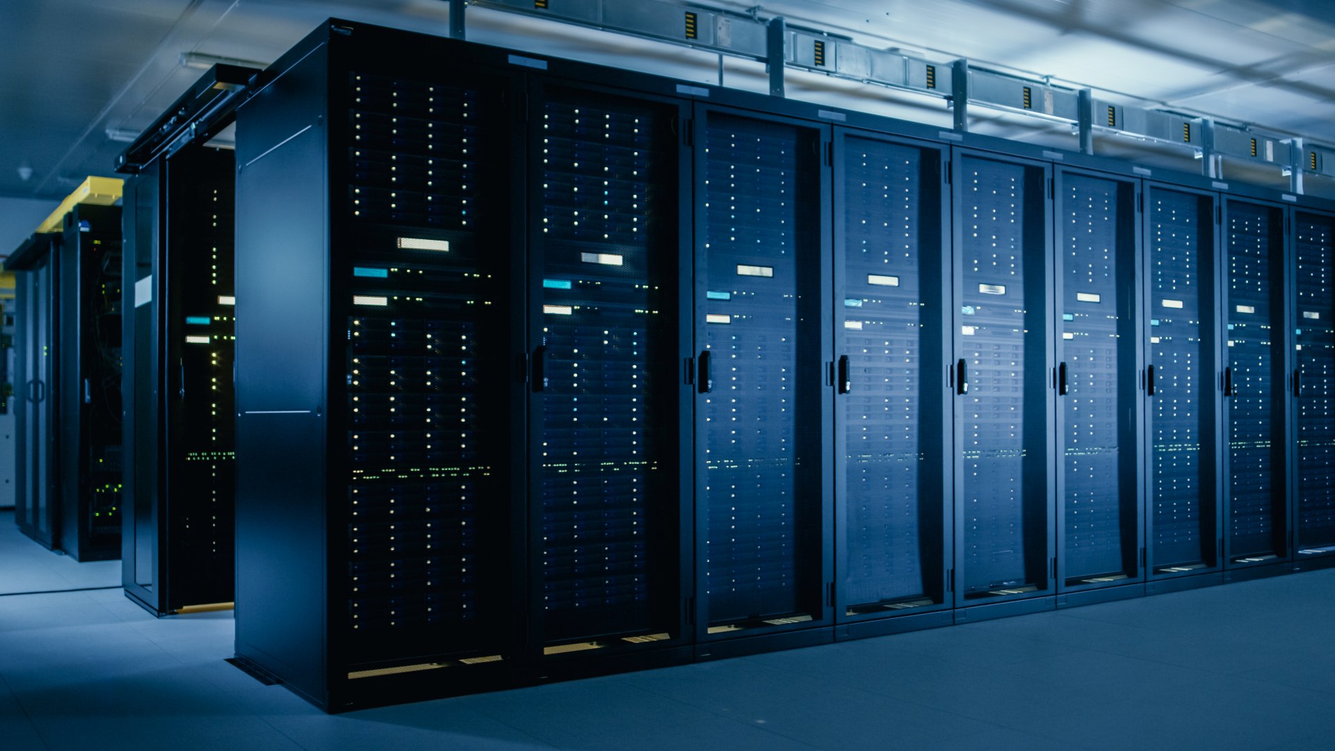 Rows of server racks with illuminated status lights inside a modern data center facility