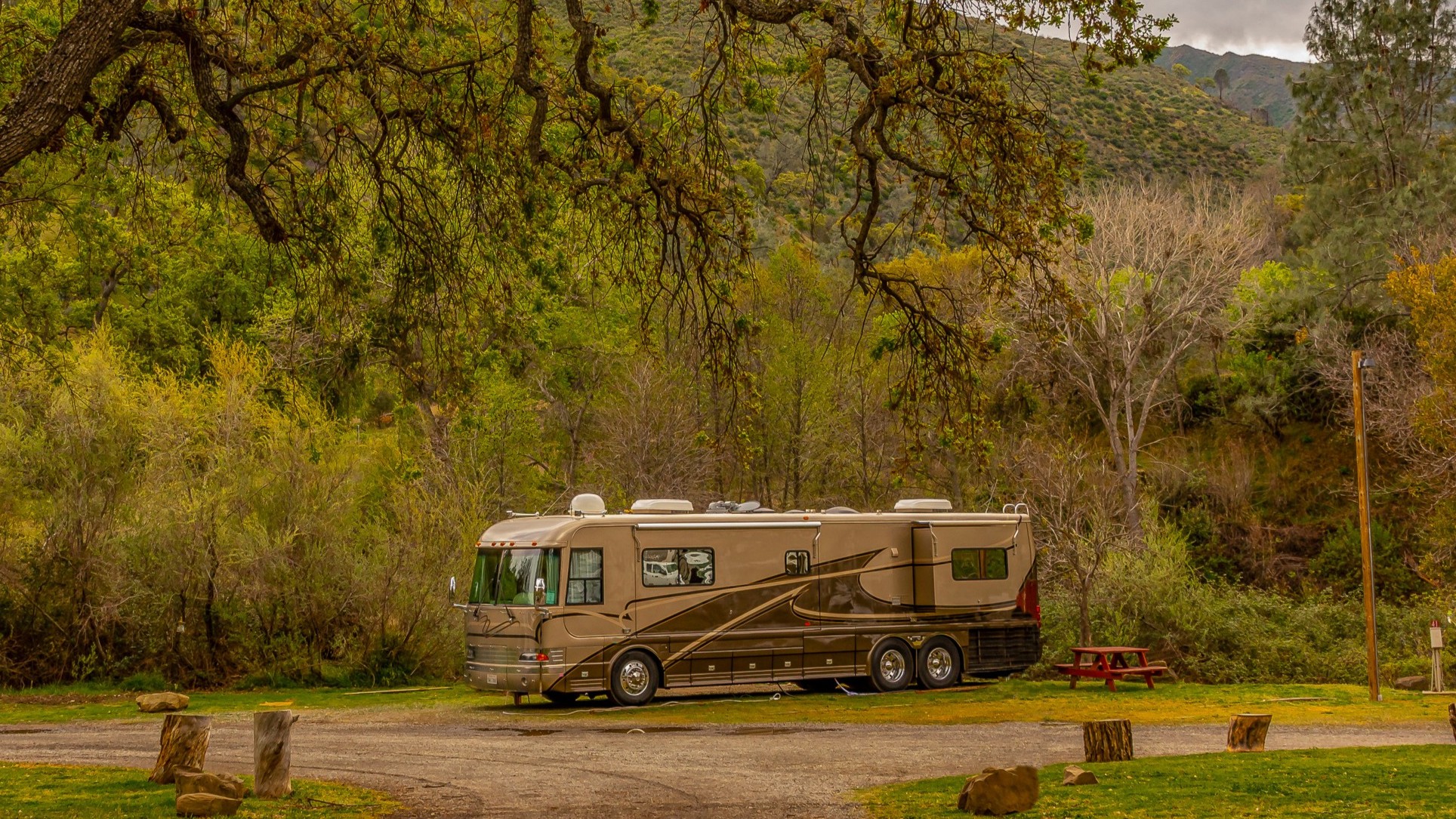 Motorhome parked at a campground surrounded by trees and mountains during an RV road trip