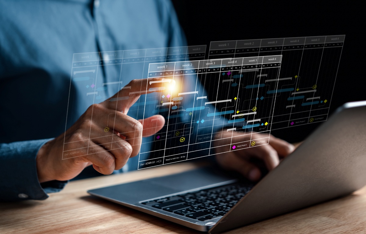 Conceptual rendering of truck fleet management through remote monitoring software floating in front of a laptop screen while a fleet manager interacts with the schedule