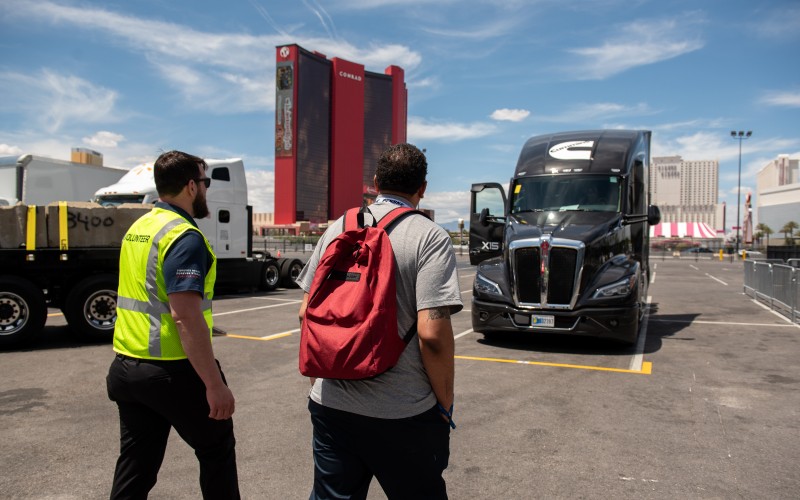Men looking at a branded Forever Rising Tour truck near the Las Vegas convention center