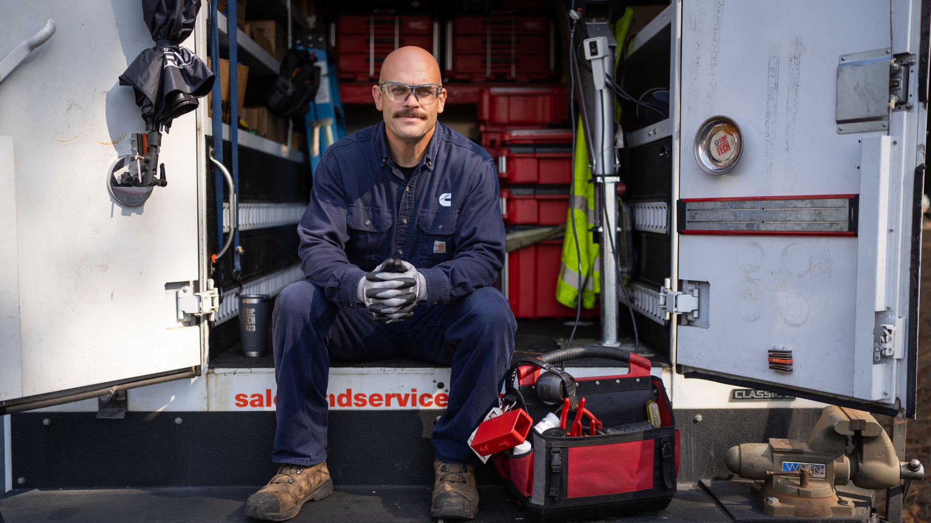 Cummins PowerGen field service technician sitting in the back of a Cummins Sales and Service truck with tools and equipment