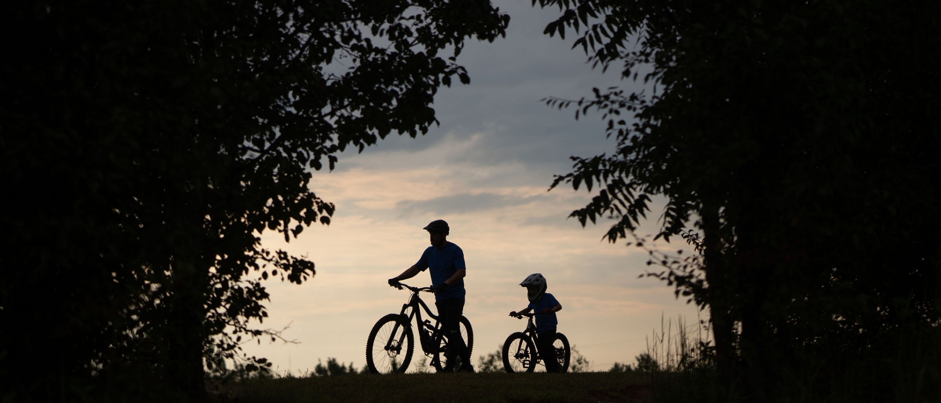 Silhouette of a father and son with bikes at sunset