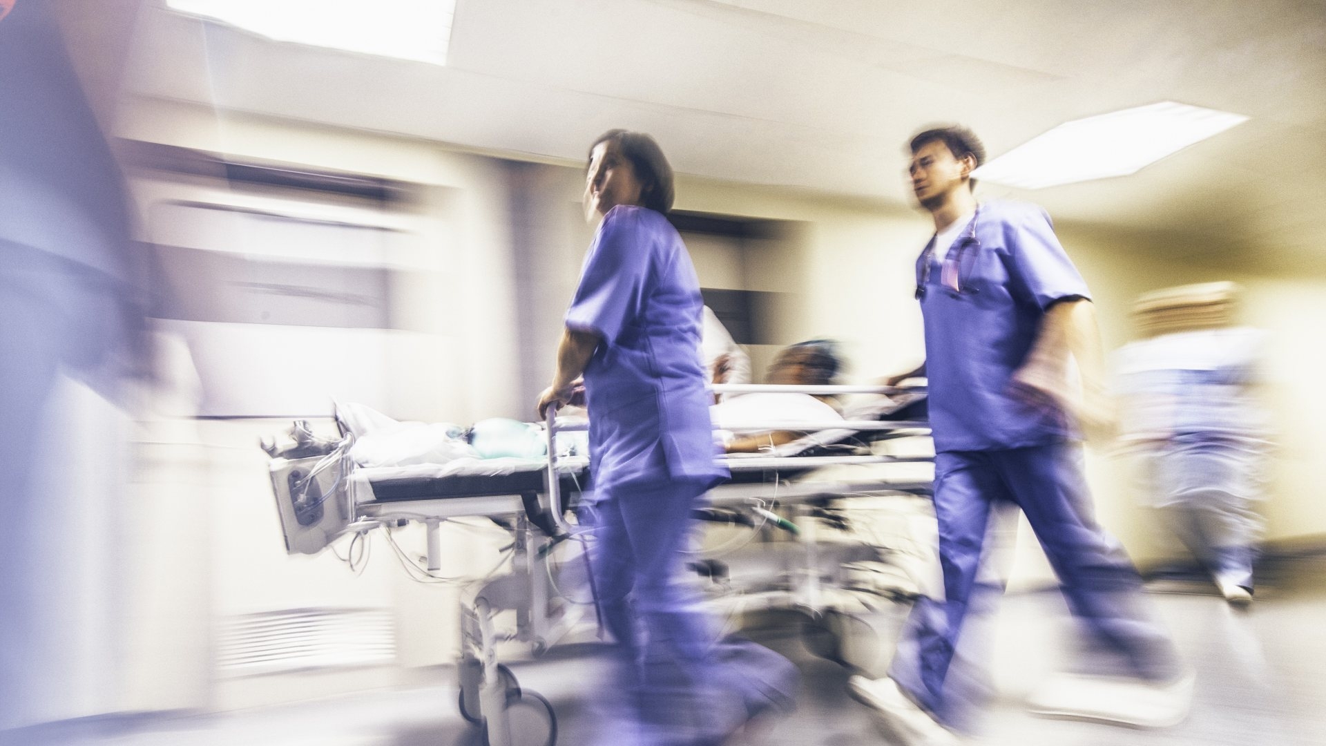 nurses carting patient in hospital hallway