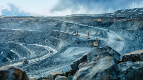 Open-pit quarry /with haul trucks and excavators operating on stepped terraces.