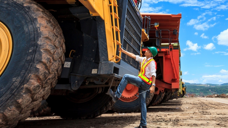 mining tech standing next to large mining tractor