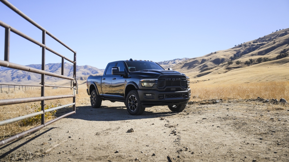 Black RAM pickup truck on a rural dirt road near rolling hills