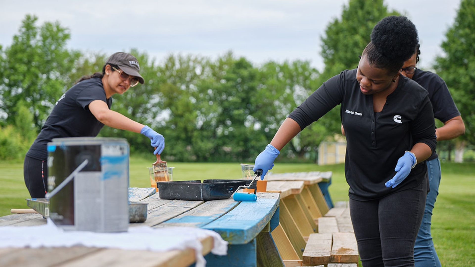 Employees painting a bench blue