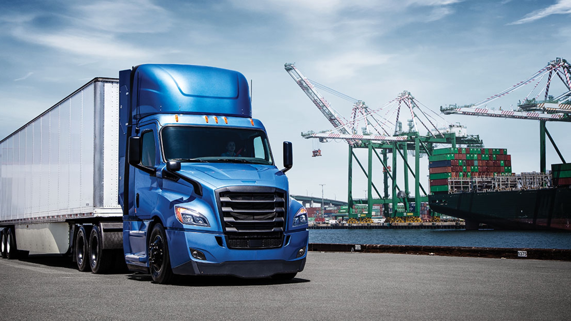 Blue and white Freightliner next to construction equipment