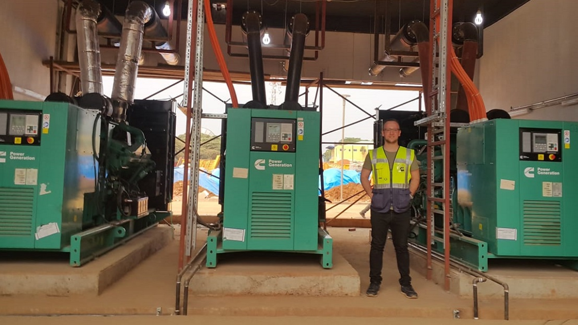 Adem Ersoy, Project Engineer at Cummins Turkey's authorized distributor Mepa Energy, stands next to the standby power system at Kigali Arena.