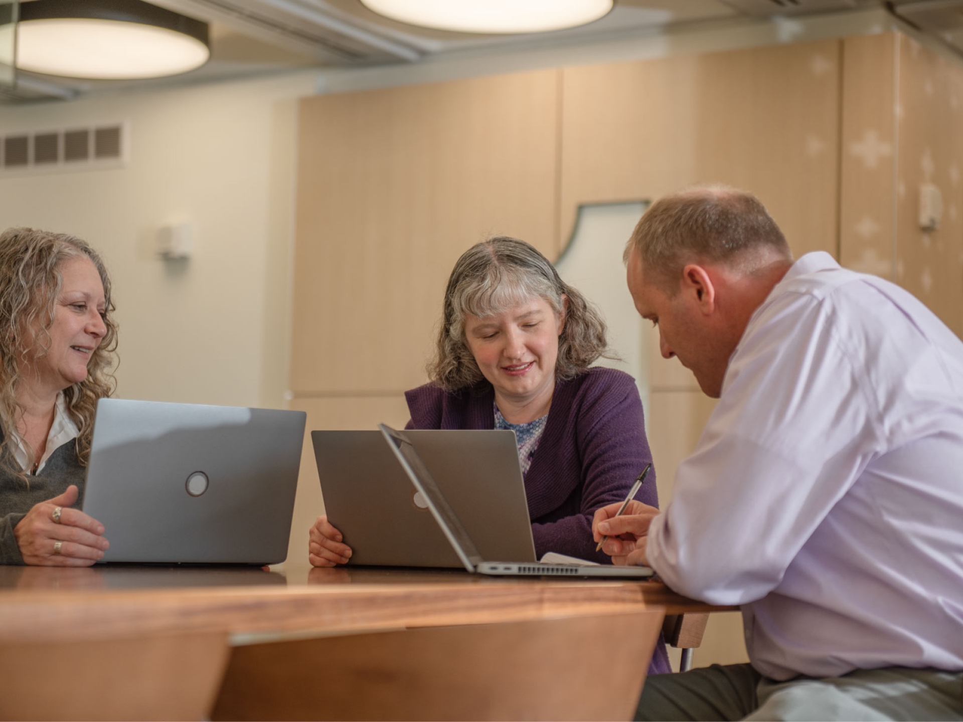 Jennifer and two colleagues collaborate on new ideas at a table in a modern office