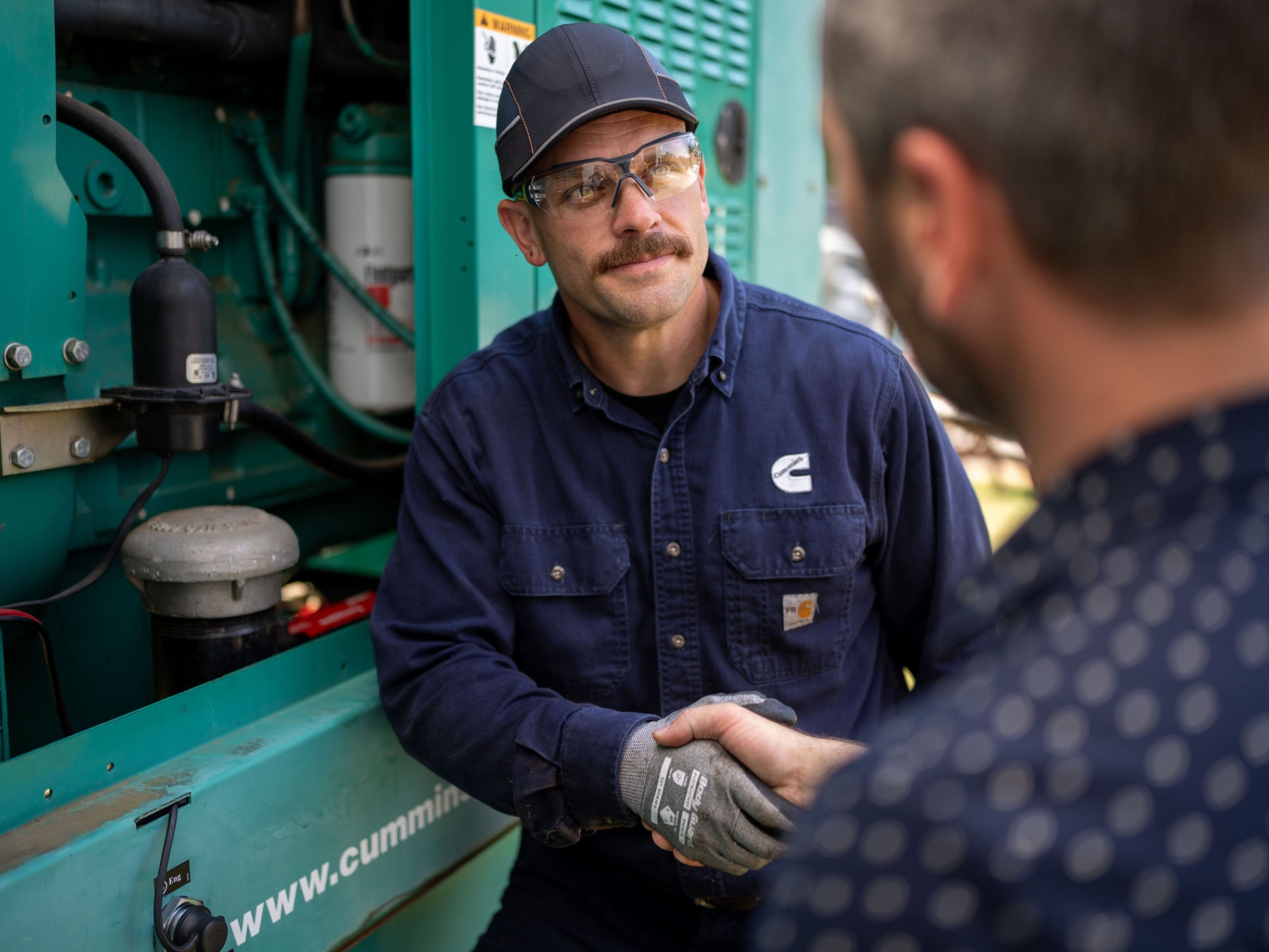 Cummins field service technician shaking hands with a customer during generator maintenance