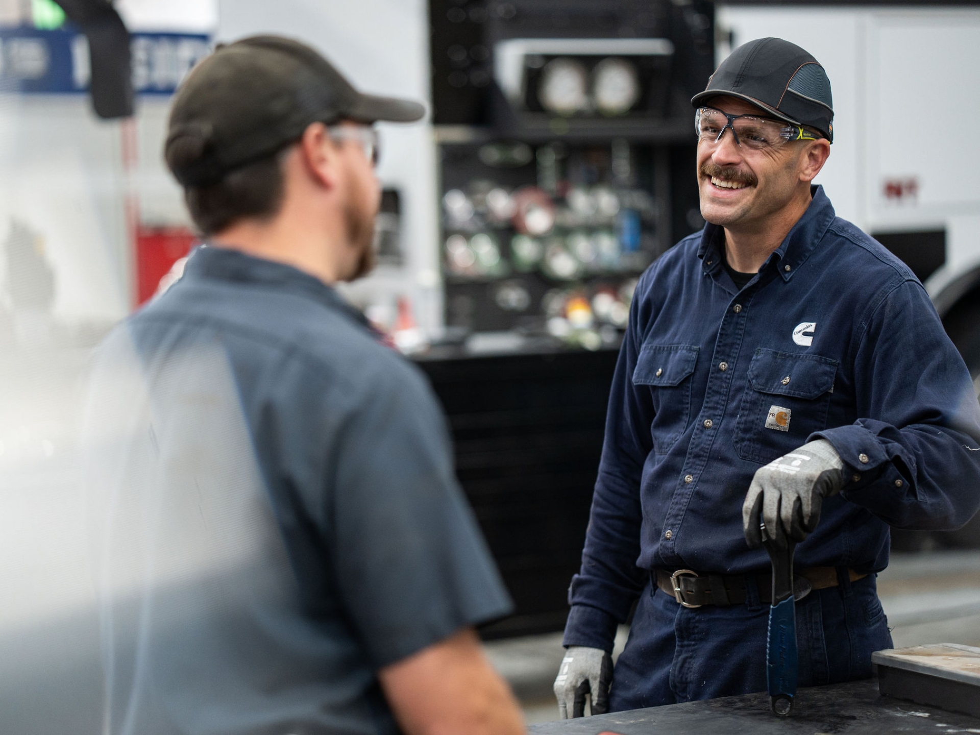 Technician discussing service work with a colleague in a shop