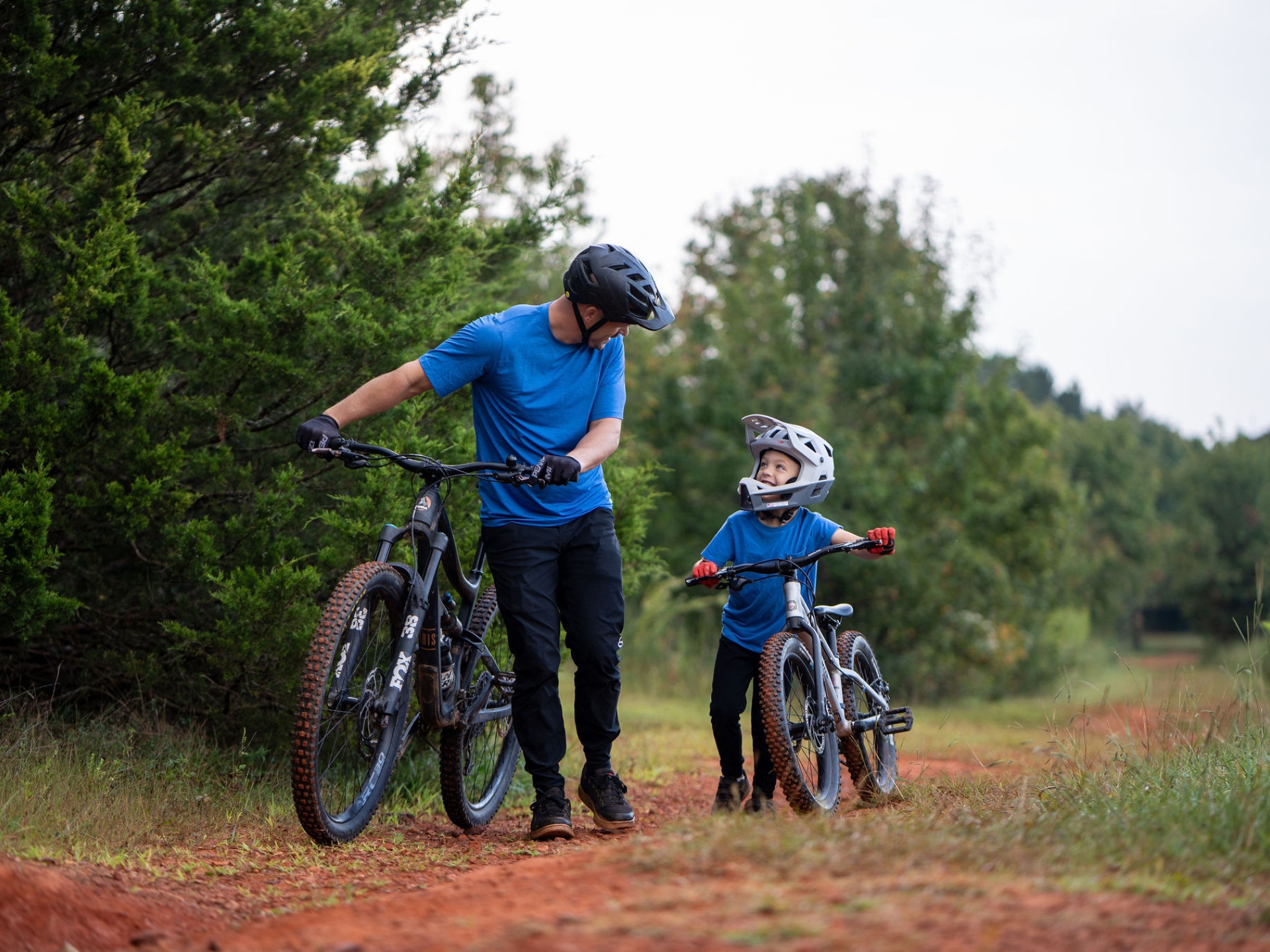 Father and son walking their bikes on a trail