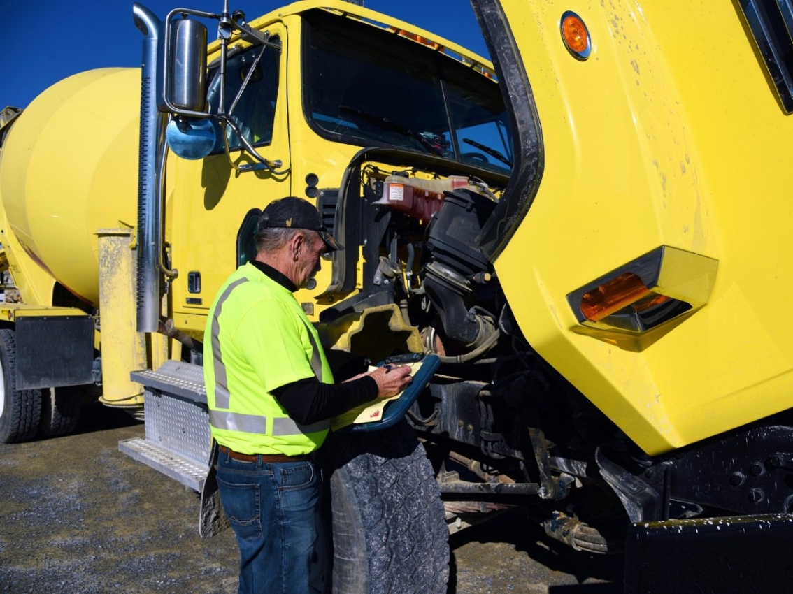 man inspecting engine for concrete mixing truck