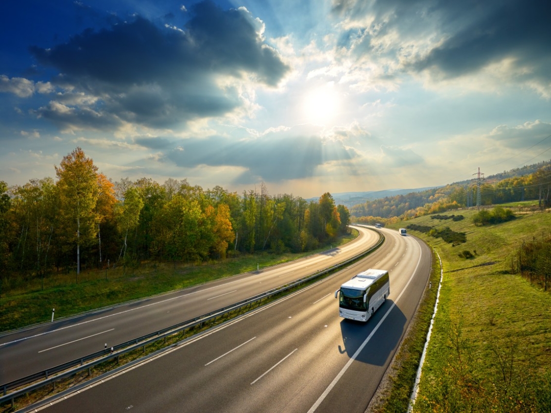 Bus driving on highway with the sun in the background