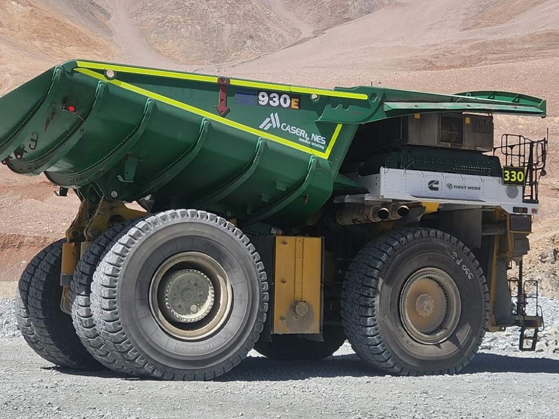 Side view of a large mining haul truck with a green haul body