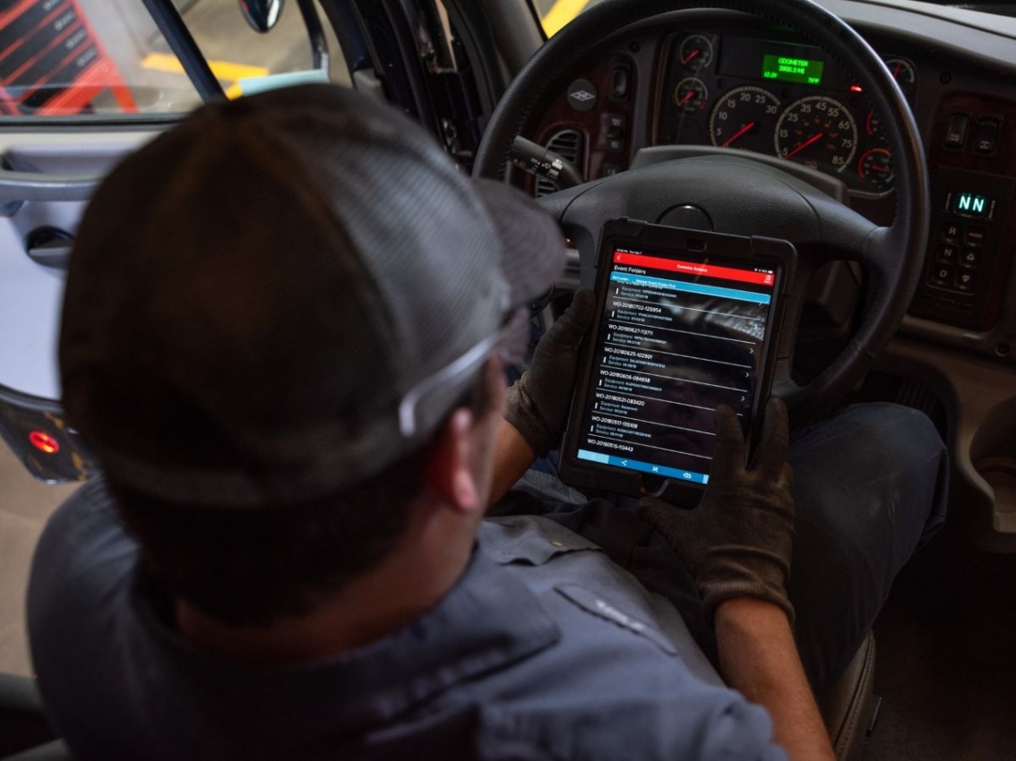 Technician using Cummins Connected Solutions on a tablet inside a truck cab