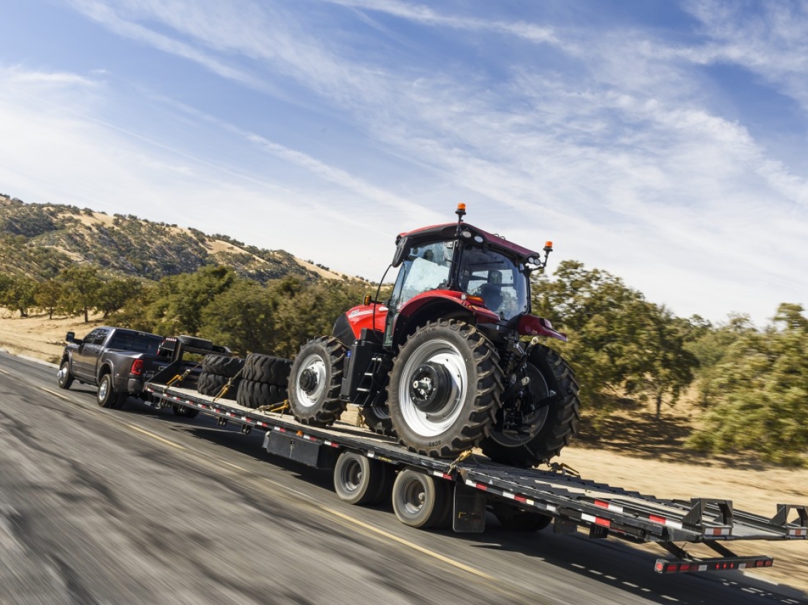 Pickup truck towing a tractor on a flatbed trailer